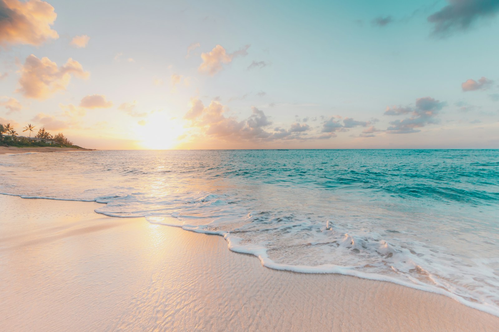 Turquoise ocean waves washing onto a sandy beach at sunrise — branded watersports accessories for NZ and AU retailers